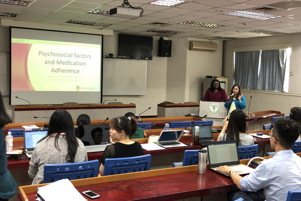 CMU research presentation Olayinka Shiyanbola standing at podium in China Medical University's lecture hall