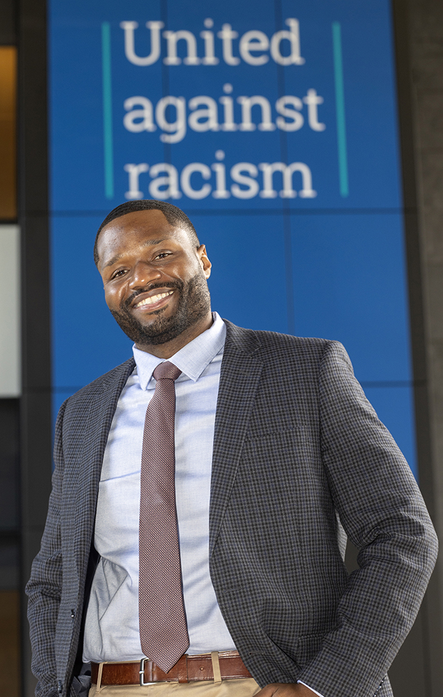 Jevon Oliver standing in front of a banner that reads "United Against Racism."