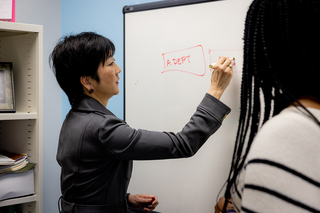 Michelle Chui writes on a whiteboard next to Olayinka Shiyanbola