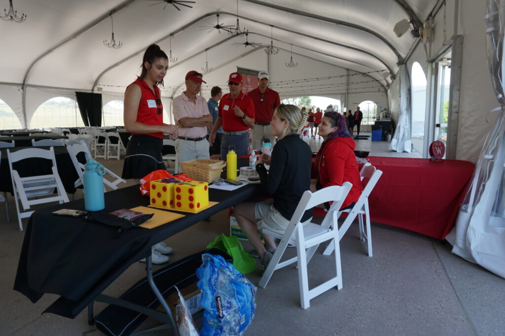 DSC07274 Event coordinators at a table with props and tickets under a large pavillion.