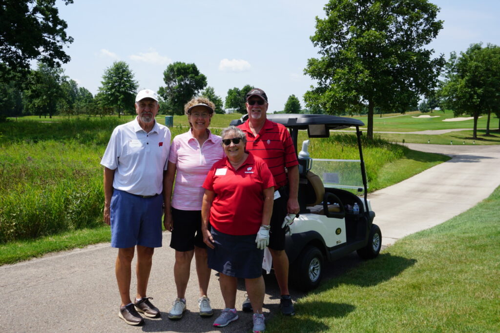 DSC07331 Alumni taking a group picture together next to a golf cart at a golf course