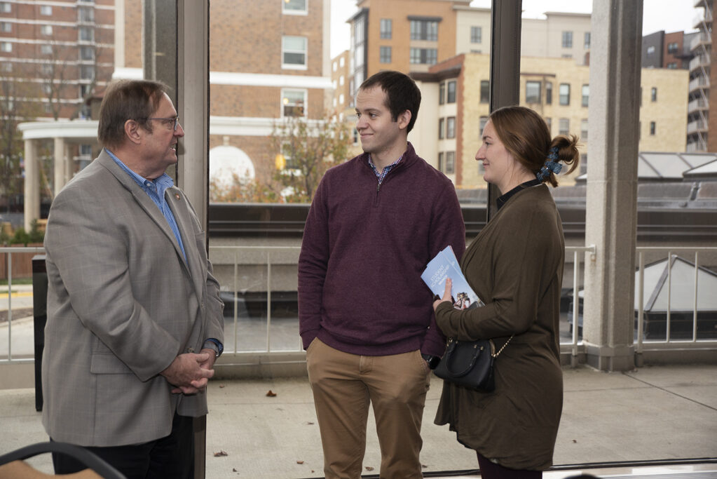 Bill Heelan and a guest speak with Dean Steve Swanson