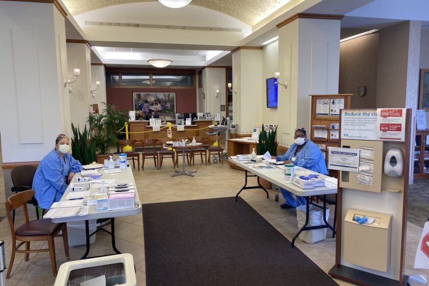 Entrance Temperature and COVID Screening Tables Folding tables set up as checkpoints with staff sitting in scrubs