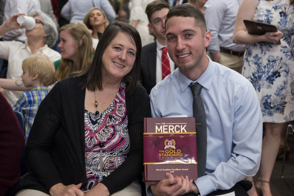 Graduation Awards Celebration_May 2018_DSC2282 Jared Baxa holding the Merck manual with his mother