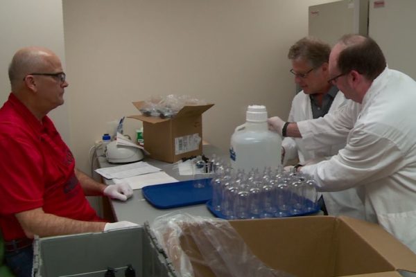 Hutson_Gidal_sanitizer Paul Hutson, Barry Gidal, and Ed Elder gathered around a table filled with supplies to fill hand sanitizer bottles