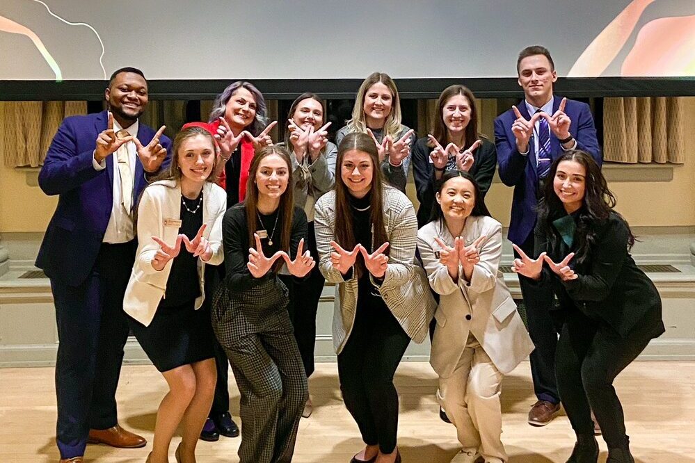 IMG6251733018409915061 PharmD students and faculty grouped together making a "W" with their hands towards the camera