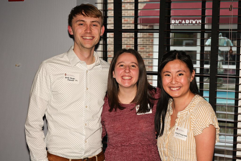 Brad Mayer, Emily Fong Velk, and another alum smile in a group
