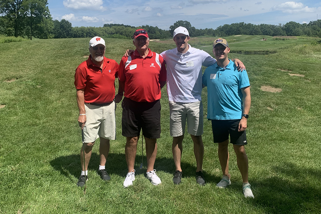 IMG_0138 A group of alumni smile at the 2022 golf outing, outside in the sun