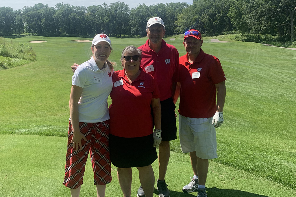 IMG_0172 A group of alumni smile at the 2022 golf outing, outside in the sun