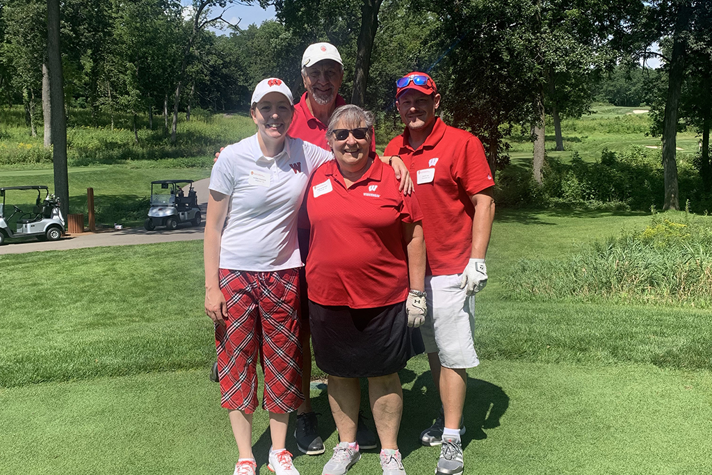 IMG_0175 A group of alumni smile at the 2022 golf outing, outside in the sun