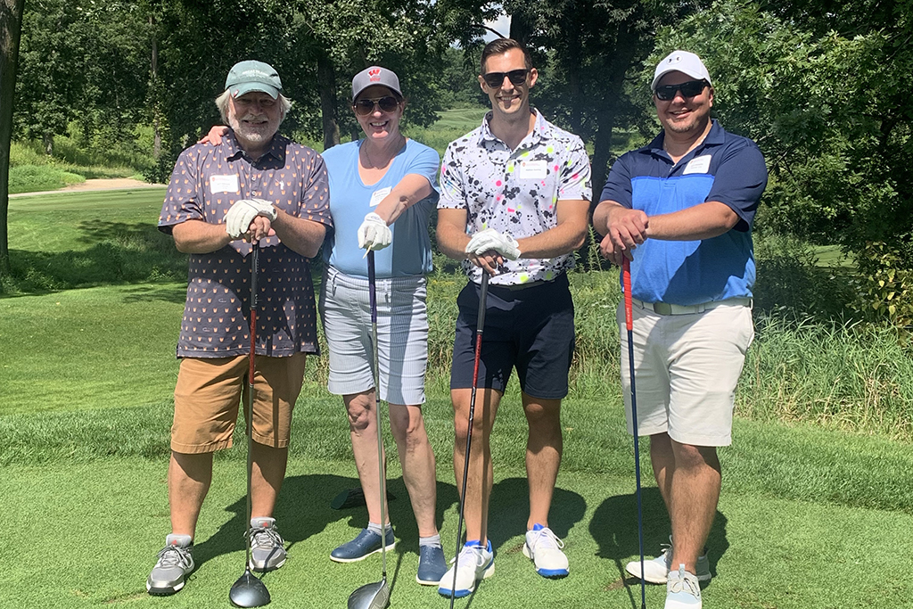 IMG_0196 A group of alumni smile at the 2022 golf outing, outside in the sun