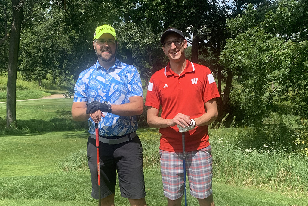 IMG_0216 A group of alumni smile at the 2022 golf outing, outside in the sun