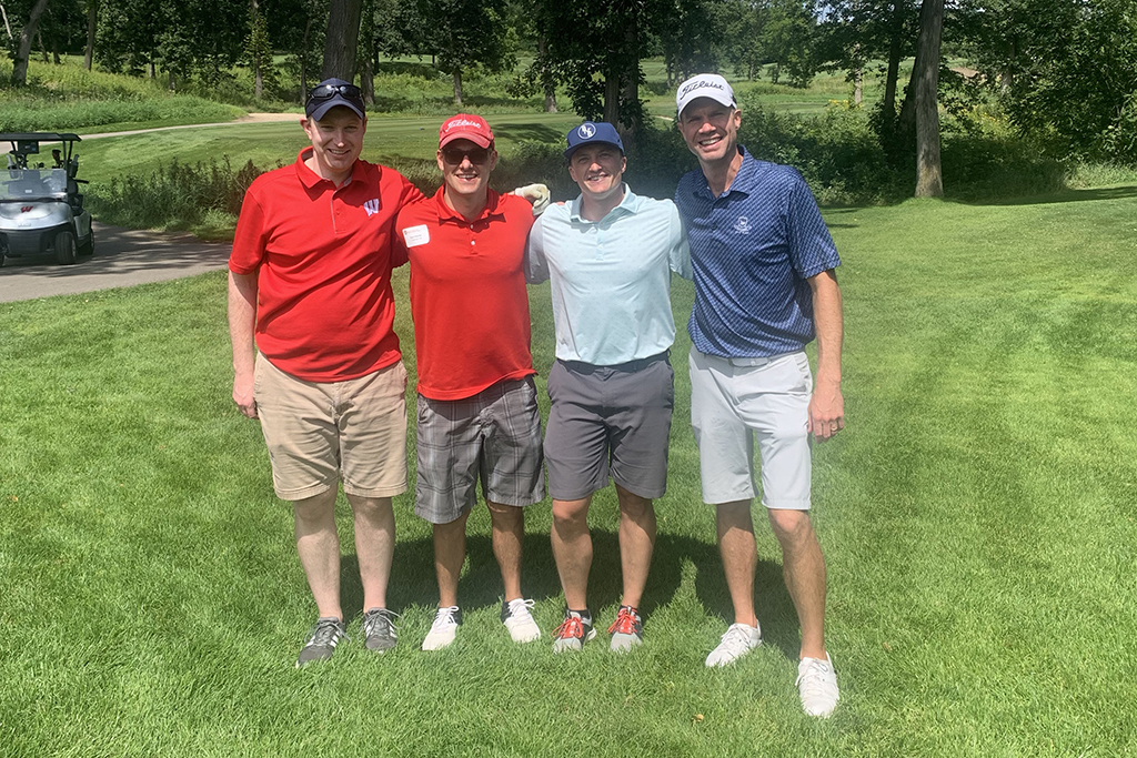 IMG_0219 A group of alumni smile at the 2022 golf outing, outside in the sun