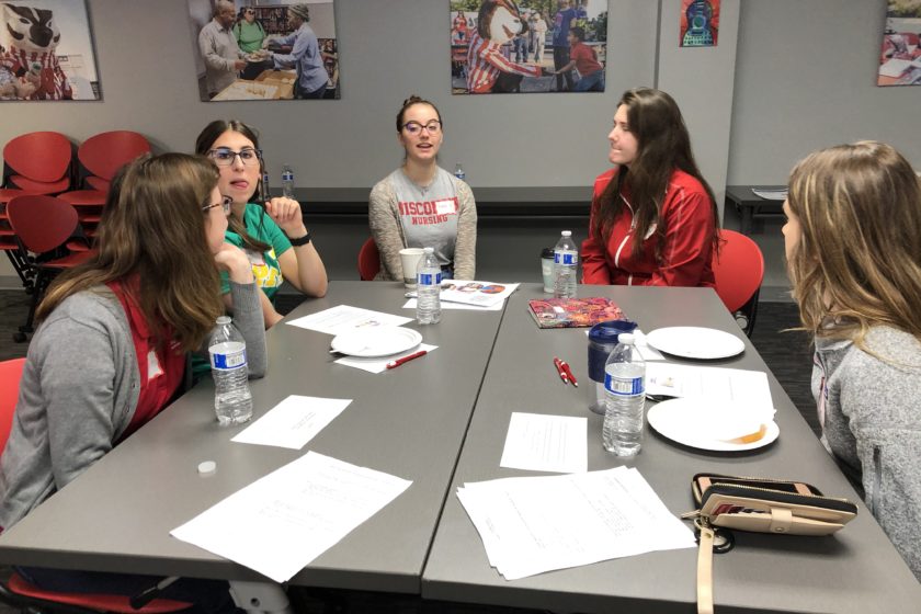 Students gathered around tables for Caring for the Caregiver event