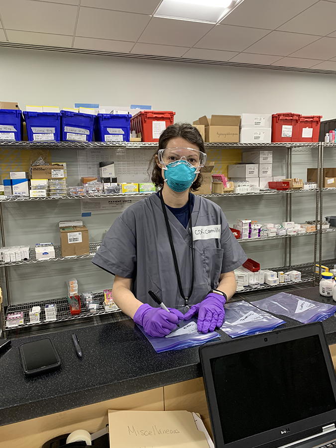 Sara Camilli, with a blue mask on, working in a pharmacy.