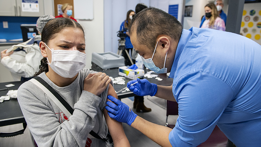 Mark Moua delivering a COVID-19 vaccine