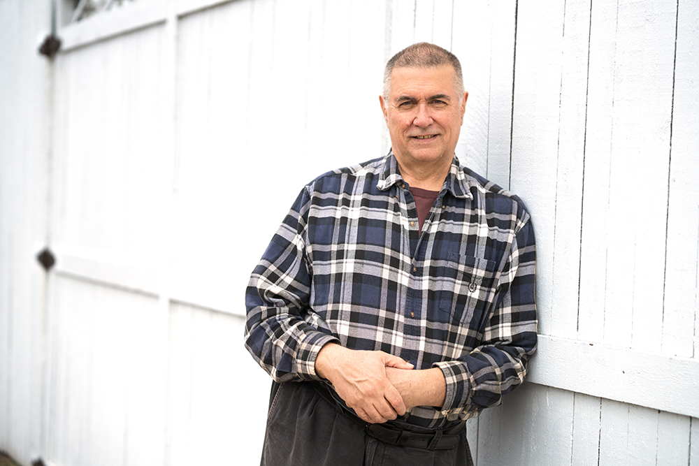 Mark Putzi leaning against a white fence