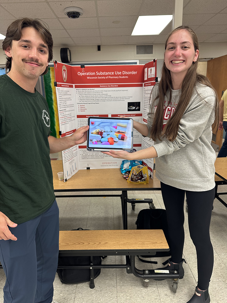 PharmD students hold a tablet at a health fair booth