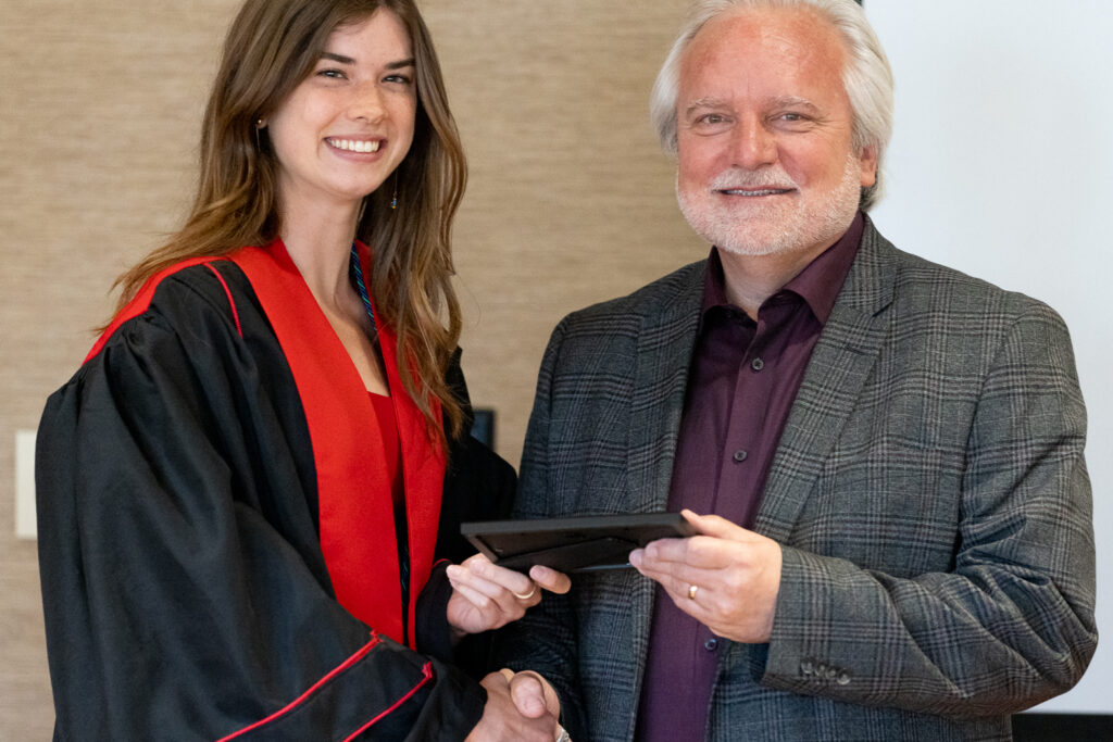 Jeff Johnson and a PharmTox graduate pose with an award.