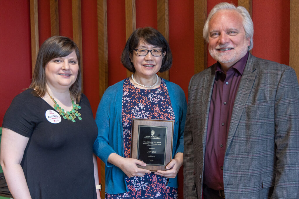 Jun Dai with an award, posing with Kendra Gurnee and Jeff Johnson.