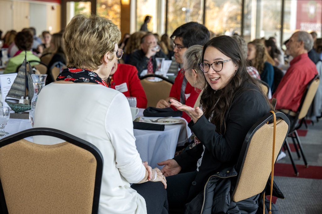 Clara Nickel gesturing and speaking to Mary Rice while seated next to each other at table