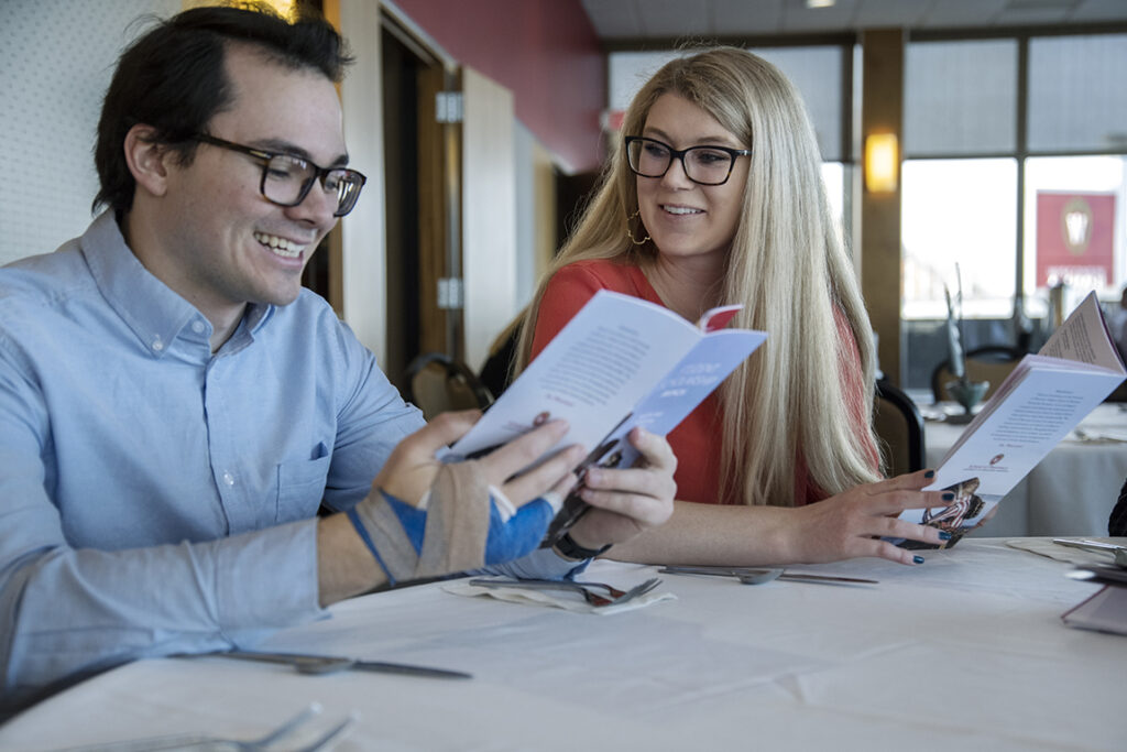 PharmD Student Scholarship Brunch_042021_BGI_5977 Christian Overman looks over the program with PharmD student Alyssa Pitterle (right) during the 2022 School of Pharmacy Scholarship Brunch