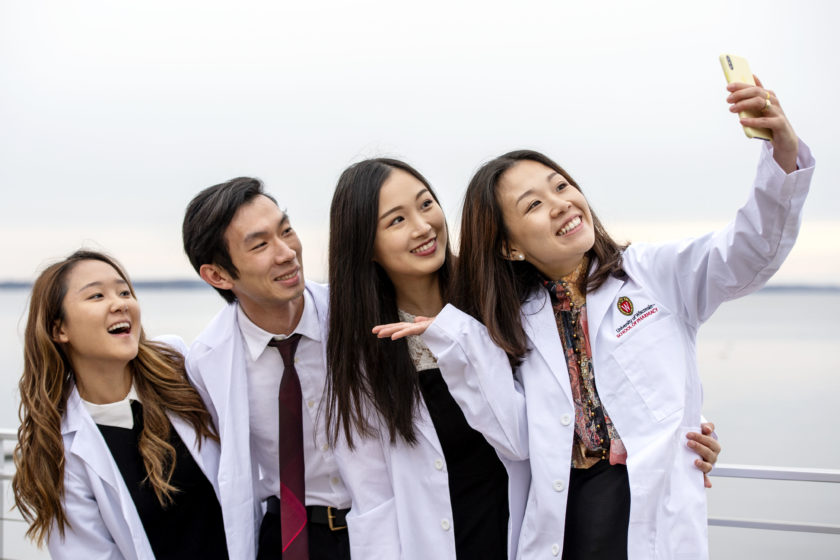 students in white coats taking a selfie together after white coat ceremony