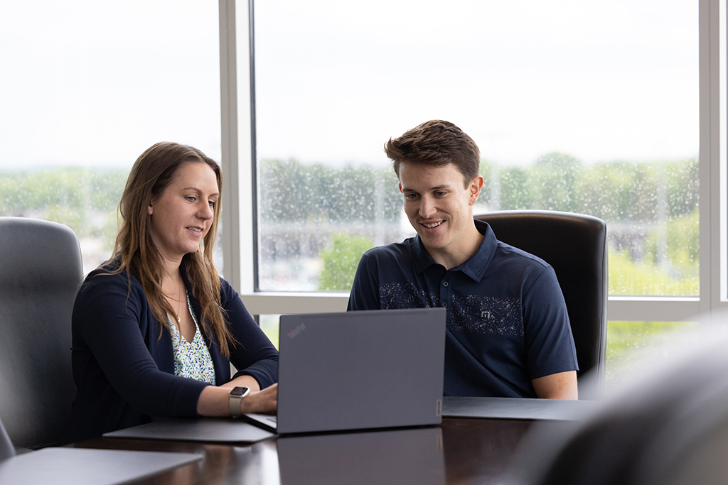 Hanna Henschel and Jacob Whitbeck discuss something over a laptop on a conference room table.