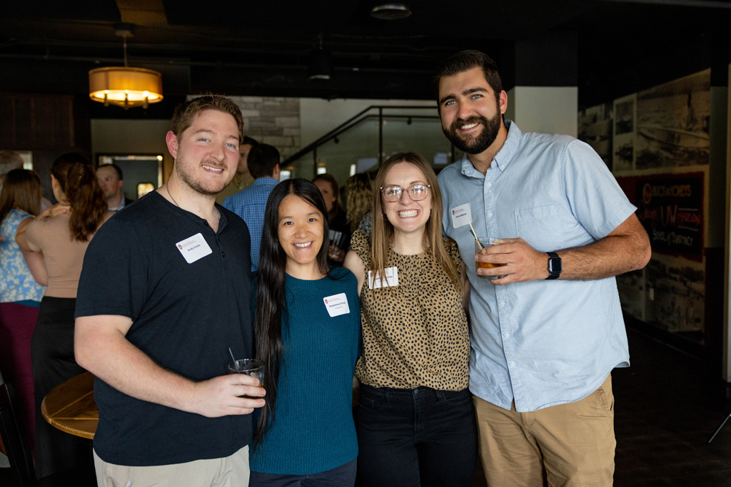 Four alumni smile for a photo
