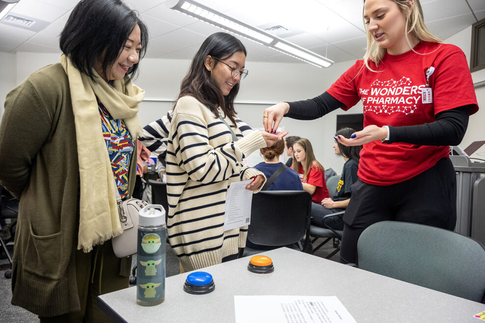 The Wonders of Pharmacy_032024_PLNZ72_6972 PharmD student Caitlin Cook hands some tokens to Diwasari Adani as she plays the PlinkRx game during the Wonders of Pharmacy on Saturday, March 2, 2024, at the School of Pharmacy on the campus of UW-Madison. (Photo Paul L. Newby, II)
