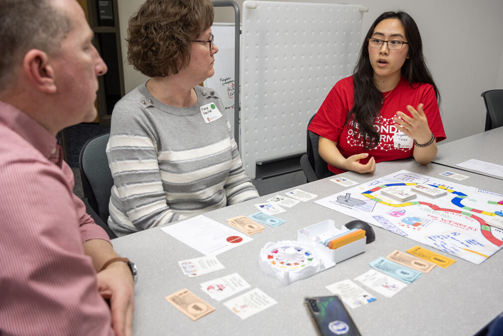 The Wonders of Pharmacy_032024_PLNZ72_7007 PharmD student Sydney Thao explains the object of the game to Sarah Kaunas' parents, Marge and Brian Kaunas, as they play the Woph Game of Life during the Wonders of Pharmacy on Saturday, March 2, 2024, at the School of Pharmacy on the campus of UW-Madison. (Photo Paul L. Newby, II)