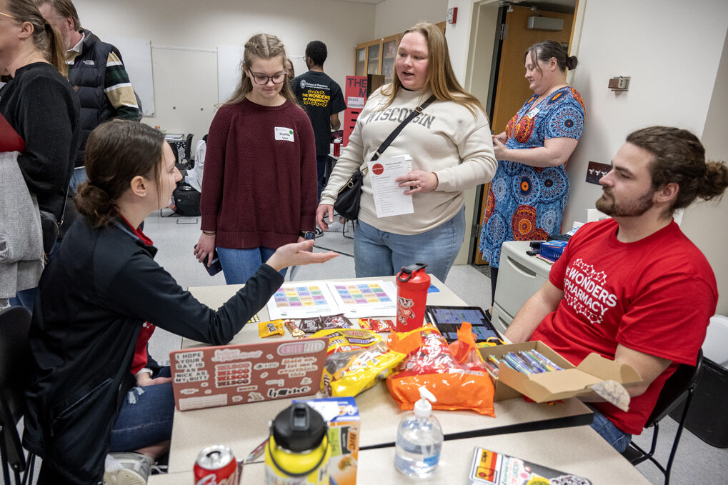 The Wonders of Pharmacy_032024_PLNZ72_7156 First-year PharmD students Megan Johnson and Elliot Quinn explain to Sophia Van and her mother, Courtney Van, how to play Pill Pursuit Bingo during the Wonders of Pharmacy on Saturday, March 2, 2024, at the School of Pharmacy on the campus of UW-Madison. (Photo Paul L. Newby, II)