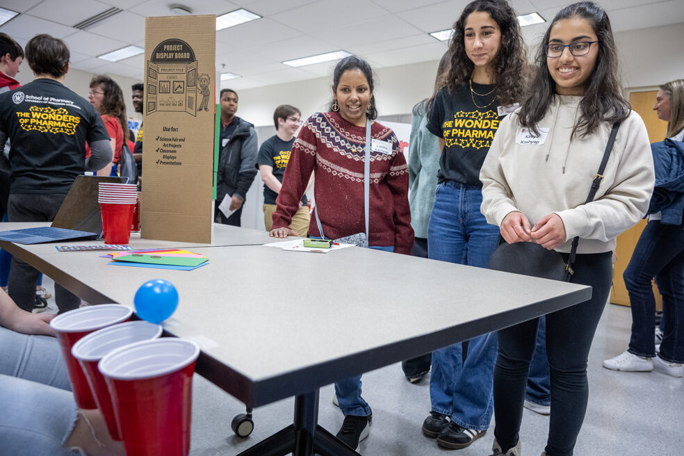 The Wonders of Pharmacy_032024_PLNZ72_7339 Kavya Kashyap watches her ball roll toward the cups as her mother, Lalitha Kashyap, and first-year PharmD student Nourhan El-Sanjak look on as she plays the Pharmacy Pipeline activity during the Wonders of Pharmacy on Saturday, March 2, 2024, at the School of Pharmacy on the campus of UW-Madison. (Photo Paul L. Newby, II)