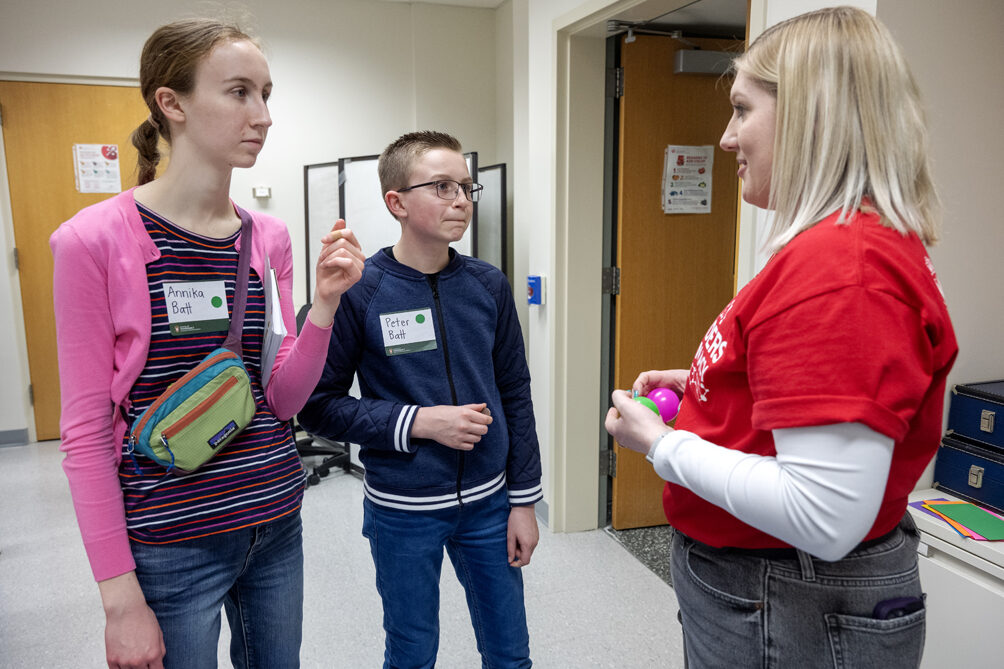 The Wonders of Pharmacy_032024_PLNZ72_7357 First-year PharmD student Lexi Wery explains the rules to Annika Batt and her brother, Peter Batt, as they prepare to play the Pharmacy Pipeline activity during the Wonders of Pharmacy on Saturday, March 2, 2024, at the School of Pharmacy on the campus of UW-Madison. (Photo Paul L. Newby, II)