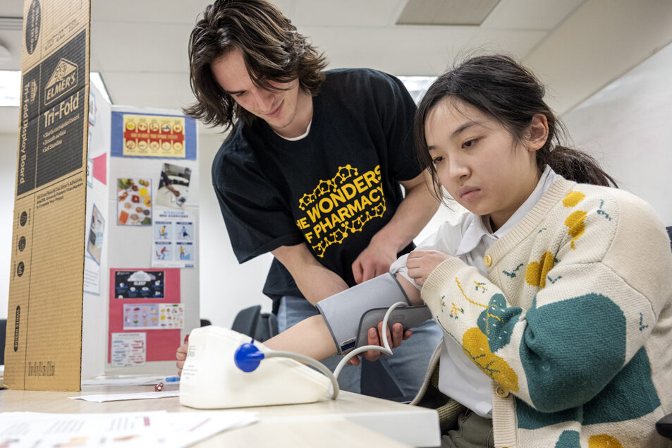 The Wonders of Pharmacy_032024_PLNZ72_7676 Third-year PharmD student Michael Milani helps Lisa Wang with the blood pressure cuff as she measures her blood pressure at the Operational PHP (Personal Health Partners) station during the Wonders of Pharmacy on Saturday, March 2, 2024, at the School of Pharmacy on the campus of UW-Madison. (Photo Paul L. Newby, II)