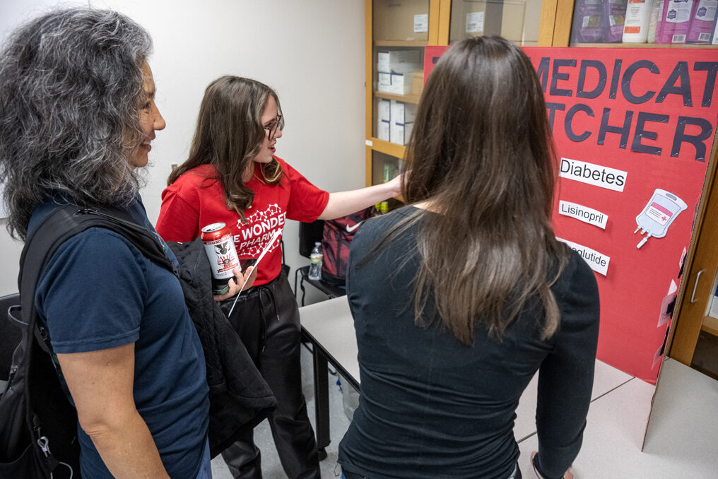 The Wonders of Pharmacy_032024_PLNZ72_7794 First-year PharmD student Maite Zapata, left, checks Kyra Anchampach's choices as her mother, Tina Wan, center, looks on as she plays the Medication Matchers activity during the Wonders of Pharmacy on Saturday, March 2, 2024, at the School of Pharmacy on the campus of UW-Madison. (Photo Paul L. Newby, II)