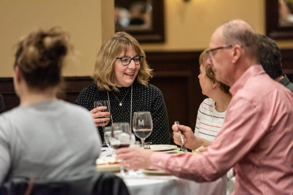 UW-Pharm-Maggianos_20220426_DSC_8476_024 Alumni speaking together around a table
