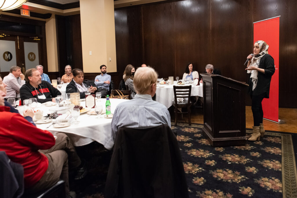 UW-Pharm-Maggianos_20220426__DSC2530_118 Dalia Saleh speaking at the podium in front of tables of people