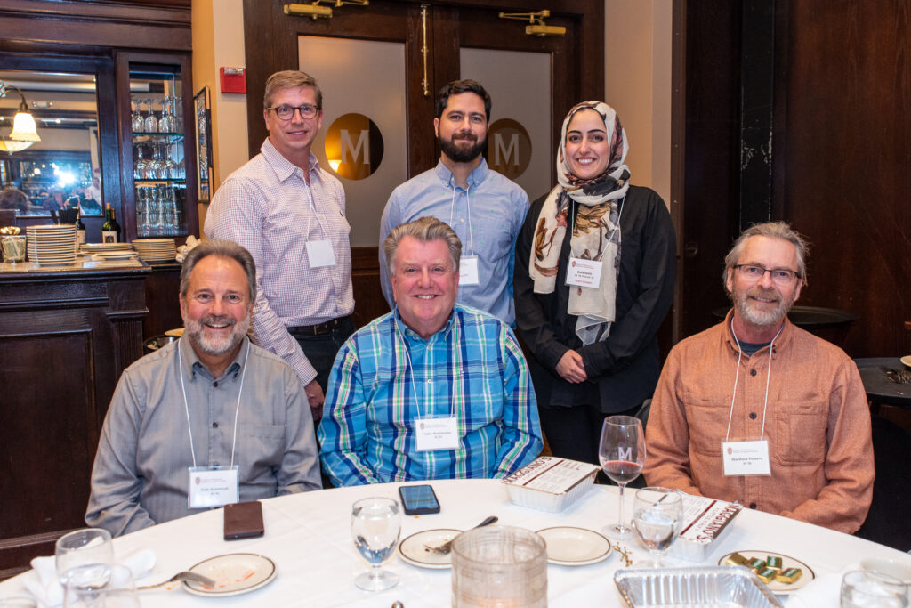 UW-Pharm-Maggianos_20220426__DSC2534_123 Alumni standing and sitting behind a table together