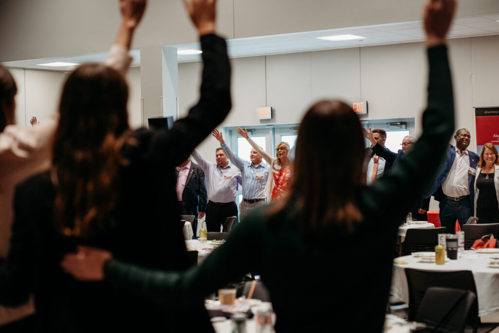 UWL-PAA-78 Alumni arm in arm, with one arm up in the air, singing Varsity, at the PAA Luncheon.