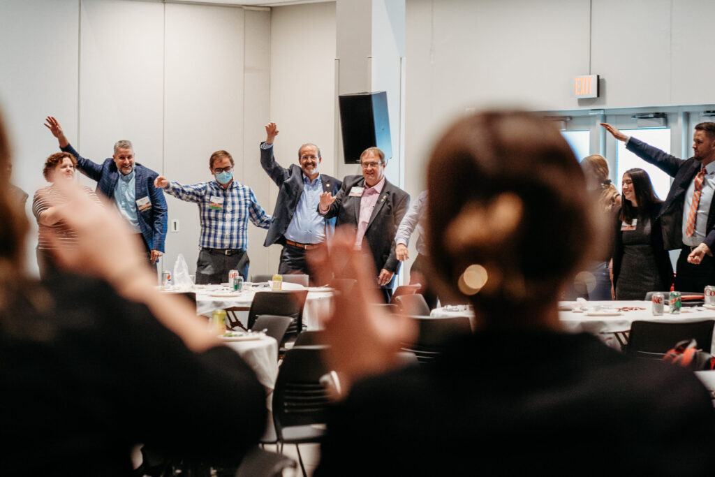 UWL-PAA-79 Alumni arm in arm, with one arm up in the air, singing Varsity, at the PAA Luncheon.