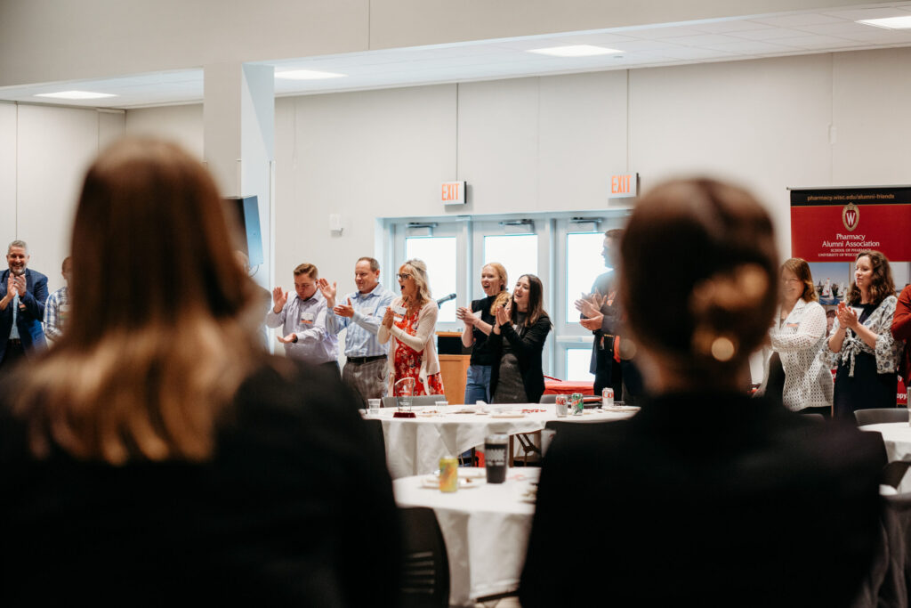 UWL-PAA-80 Alumni standing in a circle and applauding.
