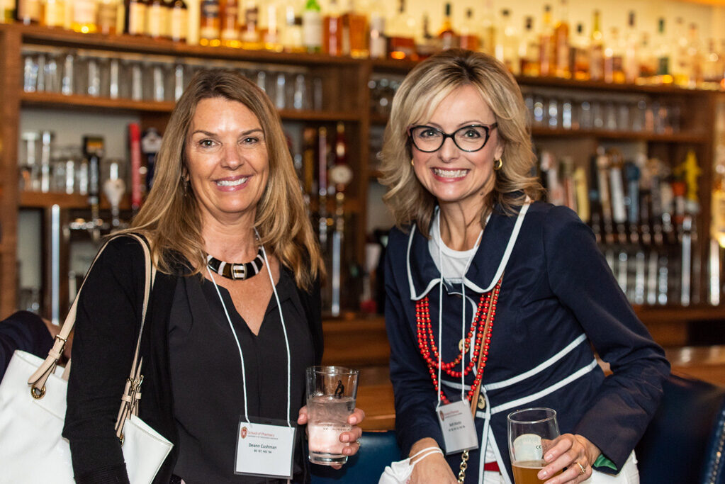 UWPharm-Coopers_2022_DSC_1479_026 Beth martin and Deann Cushman smile in front of the bar at Coopers Tavern