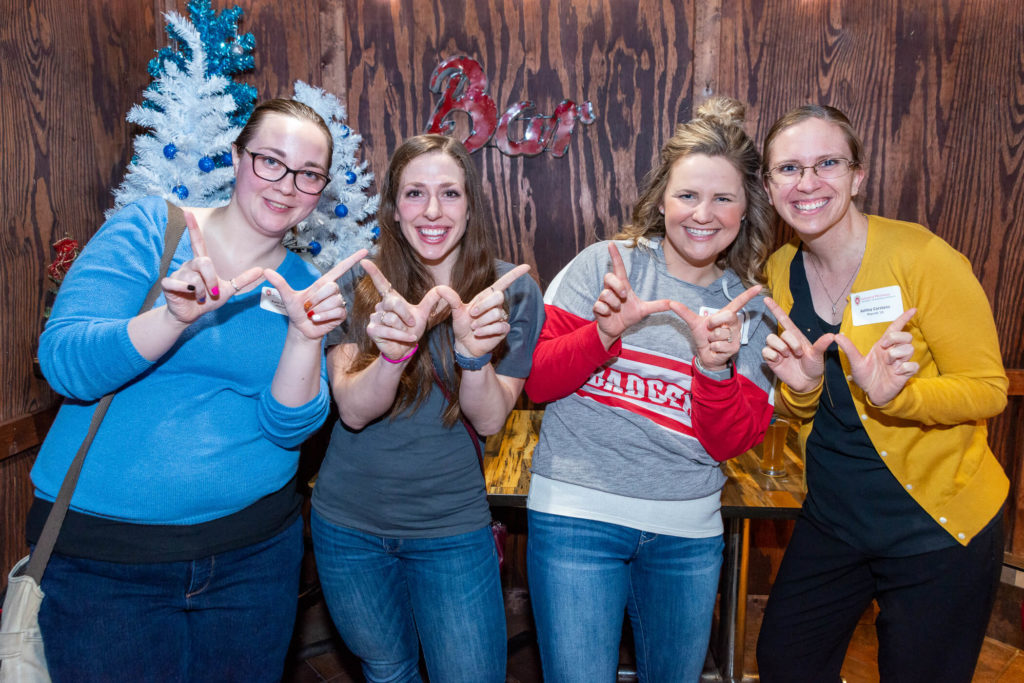 Pharmacy alumni standing altogether while forming a "W" with their hands