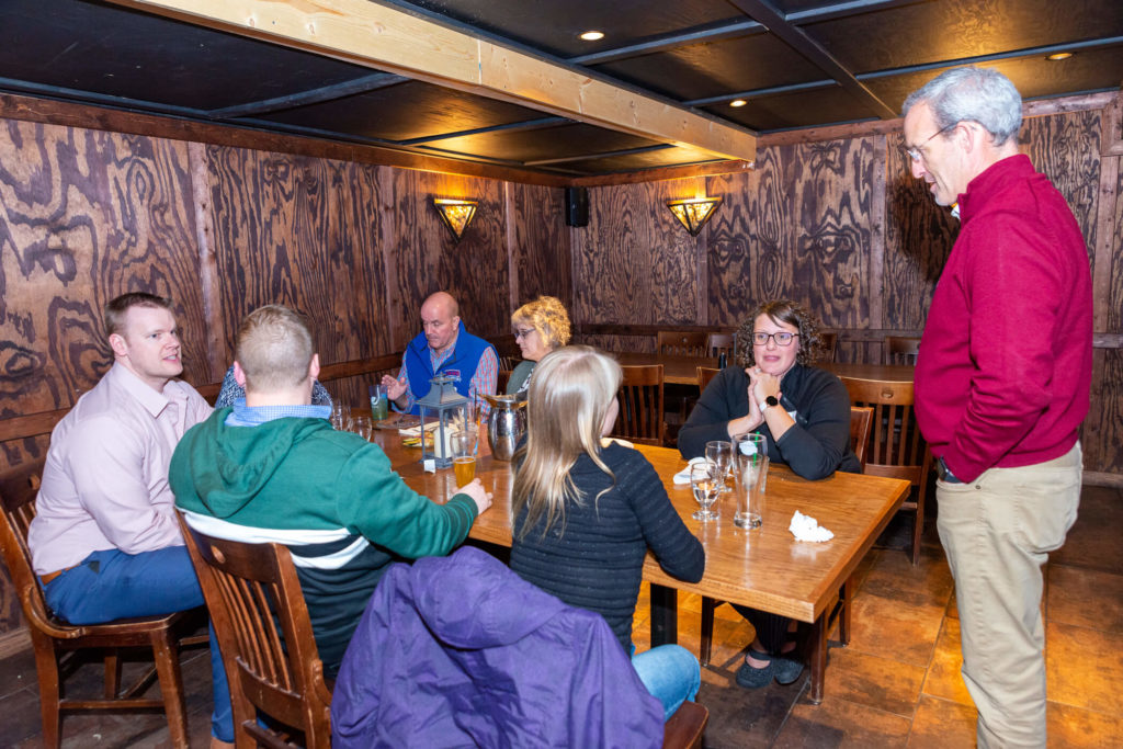 Dave Mott speaking to alumni sitting at table