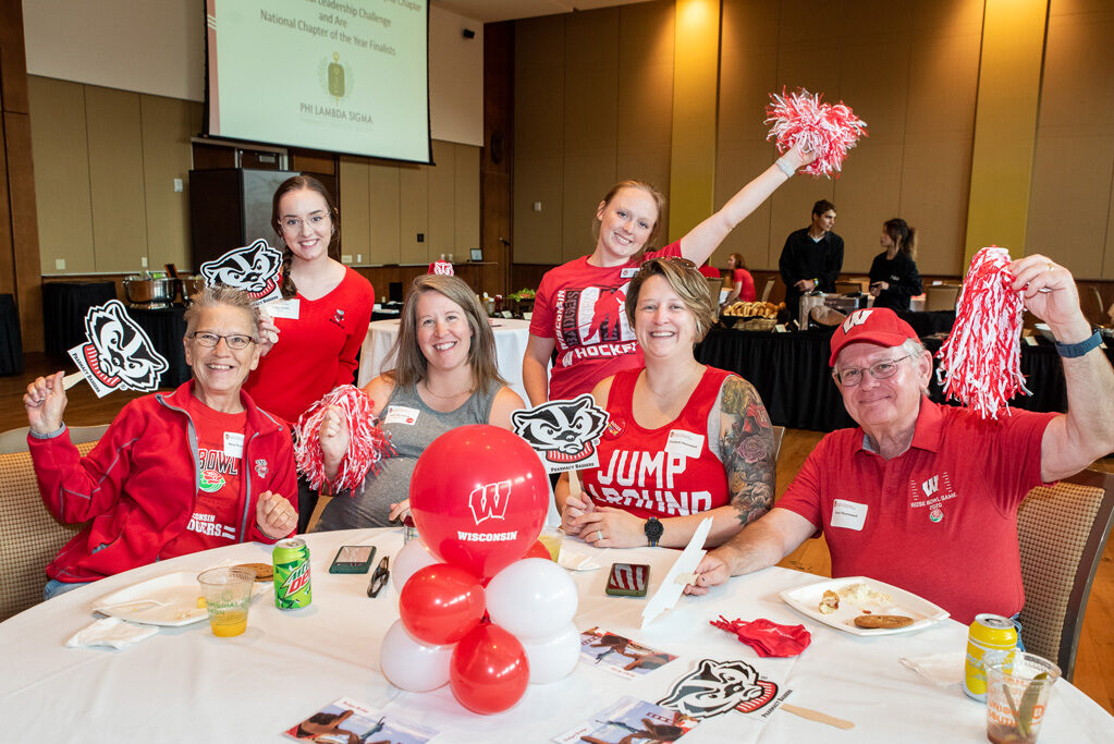 UWPharm-Tailgate_09172022_004 A group of alumni, including Patti, Steve, Mary, and Elizabeth Thornewell, smile and pose with Bucky gear.