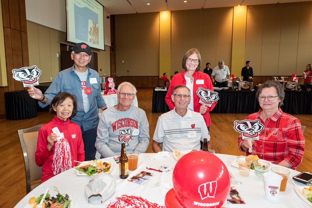 UWPharm-Tailgate_09172022_005 A group of alumni smile and pose with Bucky gear.