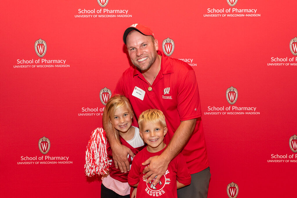 UWPharm-Tailgate_09172022_009 Matt Tepper and two young children pose and smile for a photo.