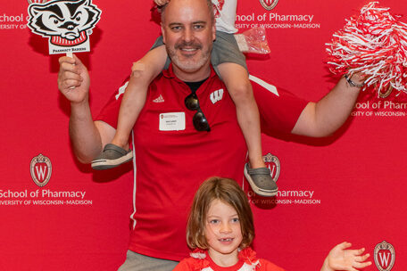 UWPharm-Tailgate_09172022_016 Nick Ladell and two young children pose with Badger gear.