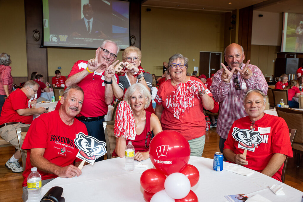 UWPharm-Tailgate_09172022_019 A group of alumni smile and pose with Badger gear.